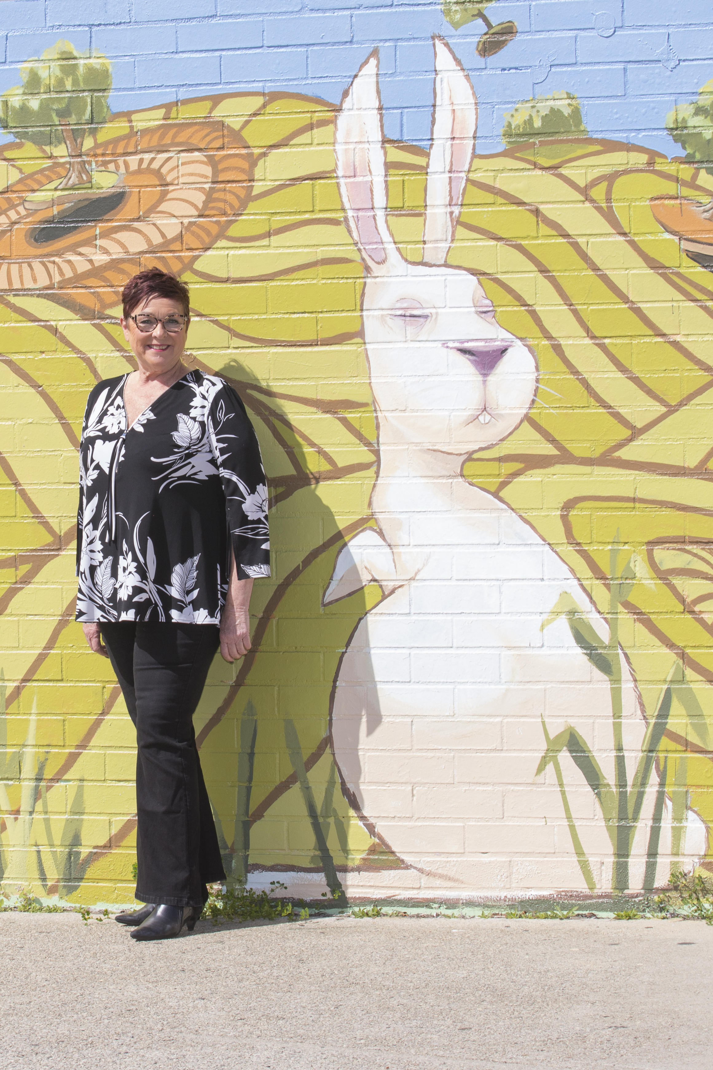 Lisa Baker MLA infront of wall with street art, of stylised rabbit and green artistic background